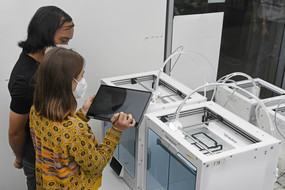 Students stand in front of 3D printers and assess progress.